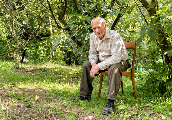 Ανώτερος άνθρωπος κάθεται σε μια καρέκλα στον κήπο — Φωτογραφία Αρχείου