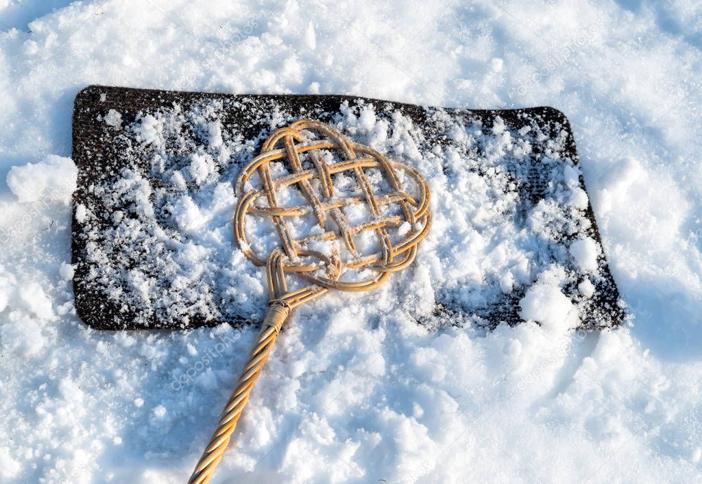 Carpet beater over carpet with snow for winter cleaning.
