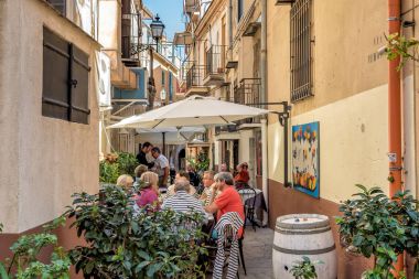 Monreale, Sicilya, İtalya - 8 Ekim 2017: Monreale tarihi merkezi dar bir sokakta dış barda oturan insanlar.