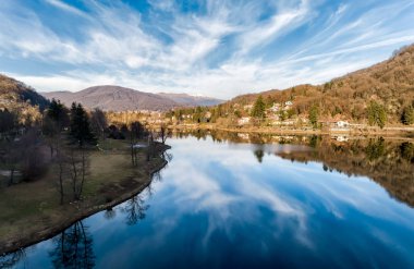 Ghirla Gölü 'nün havadan görünüşü bir kış günü bulutların ve ağaçların yansımasıyla, Valganna, Varese, İtalya