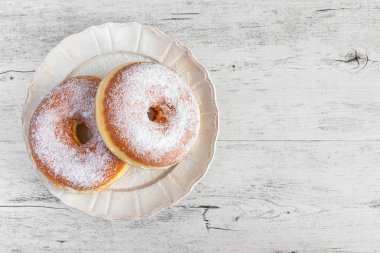 Tatlı çörek eski ahşap arka plan üzerinde plaka üzerinde şeker kaplı kızarmış.