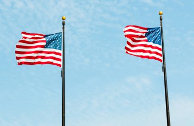 İki Amerikan bayrağı, Amerika Birleşik Devletleri ulusal bayrakları mavi gökyüzüne karşı.