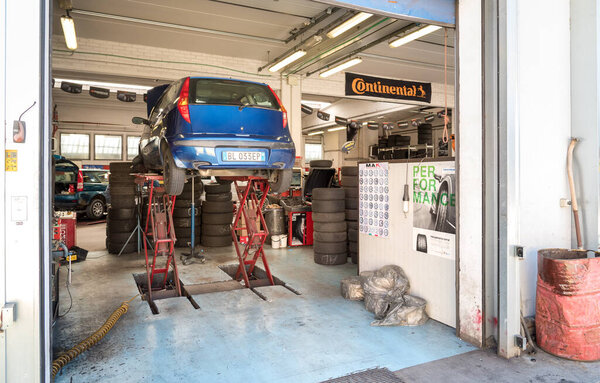 Варезе, Италия - 20 мая 2016 года: Автосервис с машинами на лифте для смены шин во время смены сезона

