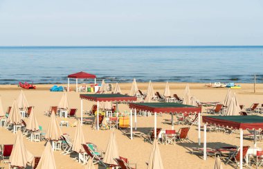 Versilia, Toskana, İtalya 'da sabahın erken saatlerinde Marina di Pietrasanta plajı beyaz kum, şemsiye ve sandalye manzarası