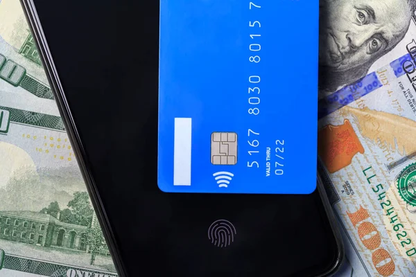 Contactless payment system. NFC payment system. A smartphone and a credit card are on dollar bills