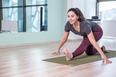 Evde yoga yapan genç bir kadının fotoğrafı. Güzel kız sınıfta yoga yapıyor. Yoga stüdyosu eğitmeni. Bulanık arkaplan