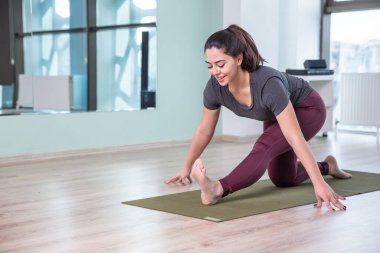 Evde yoga yapan genç bir kadının fotoğrafı. Güzel kız sınıfta yoga yapıyor. Yoga stüdyosu eğitmeni. Bulanık arkaplan