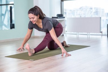 Evde yoga yapan genç bir kadının fotoğrafı. Güzel kız sınıfta yoga yapıyor. Yoga stüdyosu eğitmeni. Bulanık arkaplan