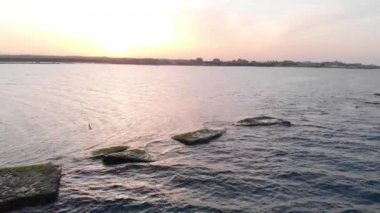 Plaj manzarası, tropik sarı kumsalda dalgalar kopuyor. Sarı kumsalda deniz dalgaları. Kum kıyısındaki mavi deniz suyunun üstündeki video..