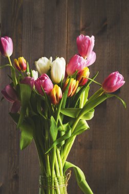 Koyu ahşap kaplamalı yapraklı lale buketi..