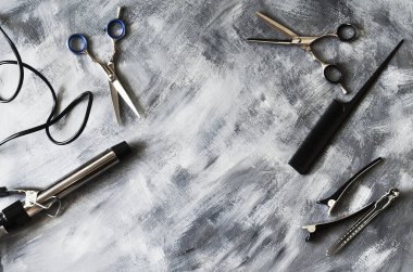 Berber aksesuarları: tarak, makas, saç maşası, saç maşası ve klipsleri, gri-beyaz arka planda yer almaktadır..