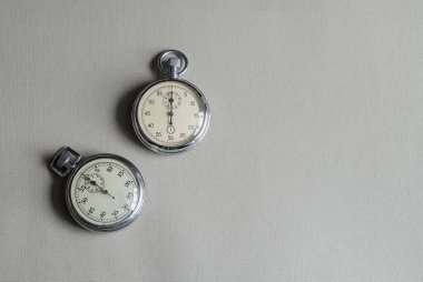 Gri arka planda duran metal çerçeveli klasik kronometreler.
