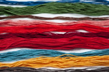 Parlak renkli nakış iplikçikleri. Koyu renk keçeli kumaş üzerine işlenmiş çok renkli iplikler. El yapımı nakış işleme arka planı