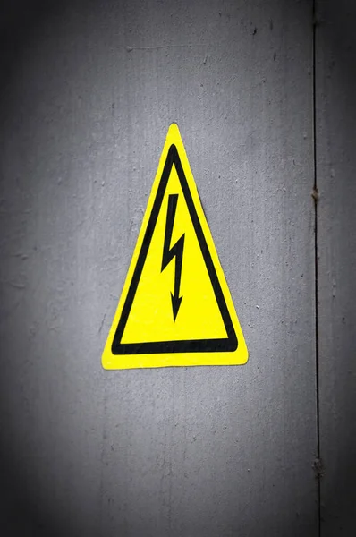 High voltage danger yellow sign on a brick wall building — Stock Photo, Image