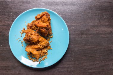 Kahverengi ahşap üzerinde açık mavi tabakta kızarmış tavuk ve kızarmış soğan. Kızarmış tavuk Hat-yai Songkhla Tayland 'ın en ünlü yemeği. Kültür yemeği. Yağlı yemek..