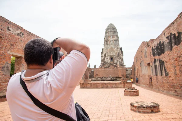 Asian Tourist man with fat take a photo ancient pagoda is buddhist temple, The most famous tourist attraction at Ayutthaya Historical park at Ayutthaya Thailand. Travel photography concept.