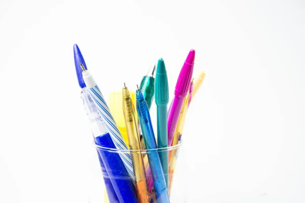 Stationery such as pen, pencil, correction pen,highlighter post it-note include the glass and have a notebook near glass on white background