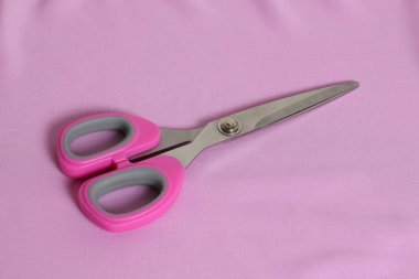 Pembe arka planda pembe saplı demir makas..