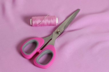 Pembe terzi makası. Dikiş ipliği, iğne.