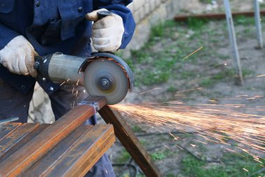 Öğütücü aletle metal kesen bir işçi. Demir öğütürken kıvılcımlar.