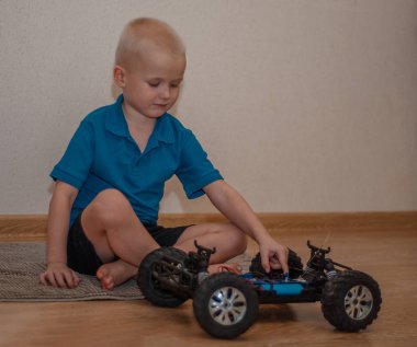 Sarışın çocuk araba tamircisi evde parçalanmış araba.