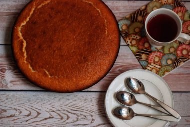 Çay için dekorasyonsuz yuvarlak kokulu kek. Hafif ahşap bir masada ev yapımı kekler. Beyaz tabaklar. Yuvarlak. Fırın ürünü. Fırından çıkan turta kendi ellerinle hazırlandı. Çay kaşığı.