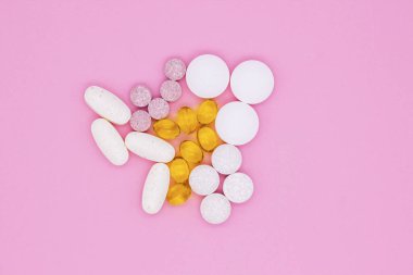 Vitaminler, haplar ve haplar. Pembe arka planda farklı vitaminler, haplar ve kapsüller..