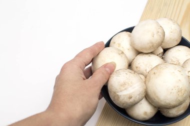 Kadın eli, tahta bir mutfak tahtasının üzerinde duran bir tabaktan şampiyon alır. Kopyalama alanı olan beyaz izole katman.