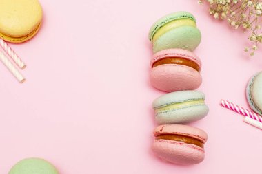 Pembe arka planda taze pembe badem kurabiyeleri ya da badem kurabiyeleri. İçecekler için kağıt boruların etrafında. Kopyalama alanı ile.