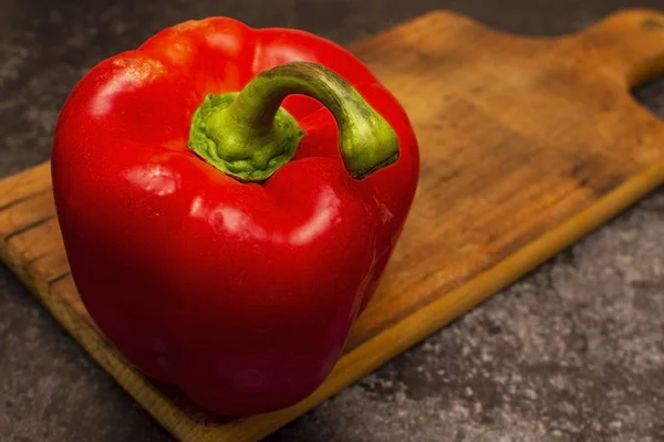 red bell pepper on a wooden board close-up, on a dark background