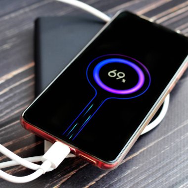 Akıllı telefon güç bankasından şarj oluyor ve şarj işlemi ekranda görünüyor.