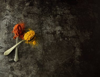 Karanlık bir arka planda kaşıklarda çeşitli baharatlar ve otlar. Yazmak için boş alan ya da yemek tarifleri.