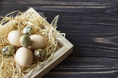 Fresh chicken and quail eggs in a wooden crate. Top view with space for copy. Natural healthy diet and organic farming concept.