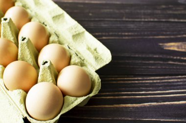 Fresh chicken eggs in a cardboard box. Top view with space for copy. Natural healthy diet and organic farming concept.