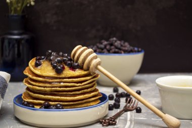 Böğürtlenli krep ve bir tabakta bal. Gözleme ve bal için kaşık..