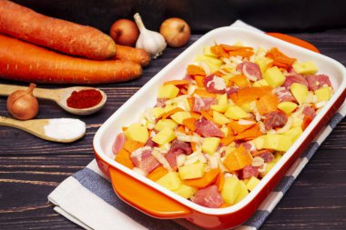 Sebzeli et güveci için hazırlık. Fırında pişirmek için dilimlenmiş et, soğan, havuç ve patates. Portakal kabında sebzeli et kebabı..