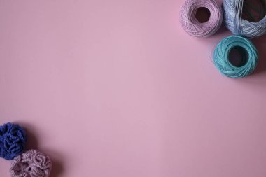 knitted flowers and skeins of yarn on a peach background. Knitting threads on a pink background. Yarn on a peach background with copy space.