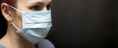 Virüs koruması. Siyah arka planda tıbbi maskeli bir kız. Coronavirüs salgını.