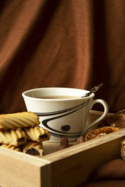 Fotokopi alanı olan ahşap bir tepside çay ve kurabiye..