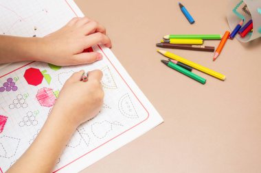 Çocuk renkli kalemlerle özel bir defterde yazmayı öğreniyor..