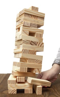 Çocuk eli Jenga oyununda tahta bir blok çizer ve beyaz izole edilmiş arka planda bir kuleyi devirir.