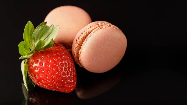 Macarons with strawberry on glass black background — Stock Photo, Image