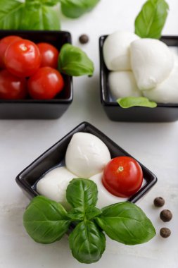 Küçük İtalyan bufalo mozzarella soslu kiraz domatesleri ve mermer tahtada fesleğen.