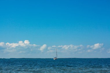 Yelkenli açık bulutlu bir gökyüzünde okyanusta yol alıyor..