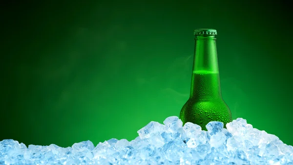 Bottle of cold beer in ice on green background — Stock Photo, Image