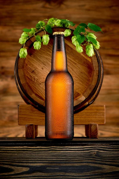 Bottle of cold beer and old barrel on wooden background — Stock Photo, Image