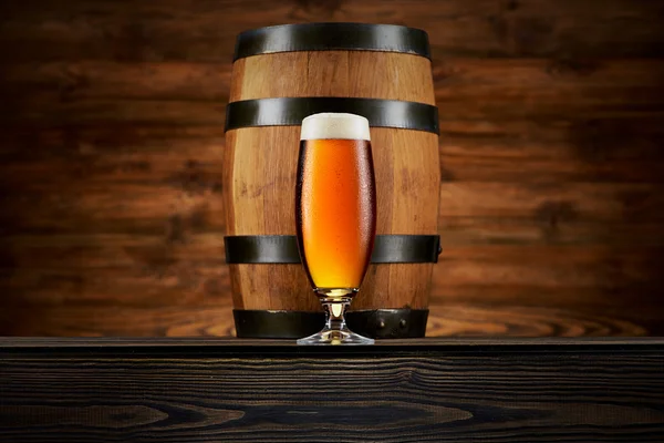 Bardak soğuk bira ve ahşap arka plan üzerinde eski varil