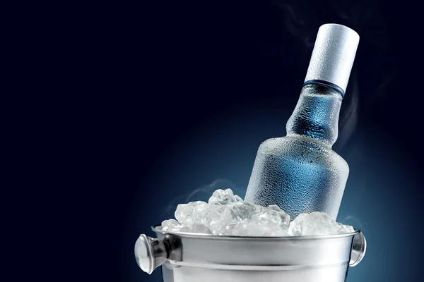 Bottle of cold vodka in bucket of ice on dark background — Stock Photo, Image