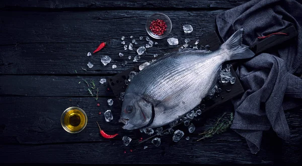 Ryby čerstvé španělské pražma (sargo) na ledě na černý dřevěný stůl — Stock fotografie