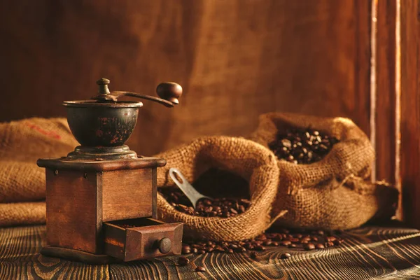 Molinillo de café y bolsa de café tostado en mesa de madera . — Foto de Stock
